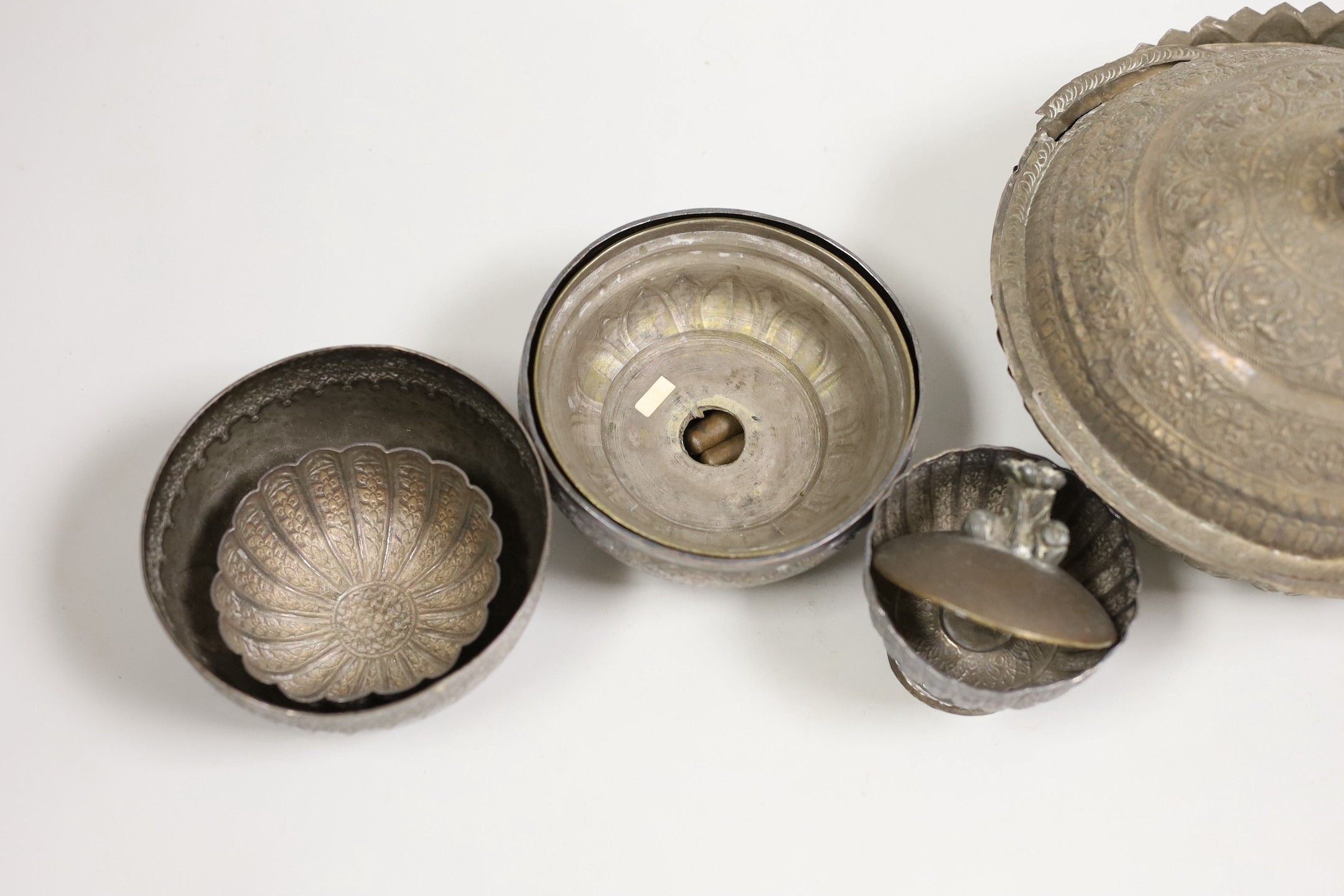 A Malay Straits pedestal bowl and cover or 'Batil Ber Tutop' (a.f.), three Malay Straits white metal betel nut cups and two similar small bowls, all with embossed floral or foliate designs (one cup with green enamelled d